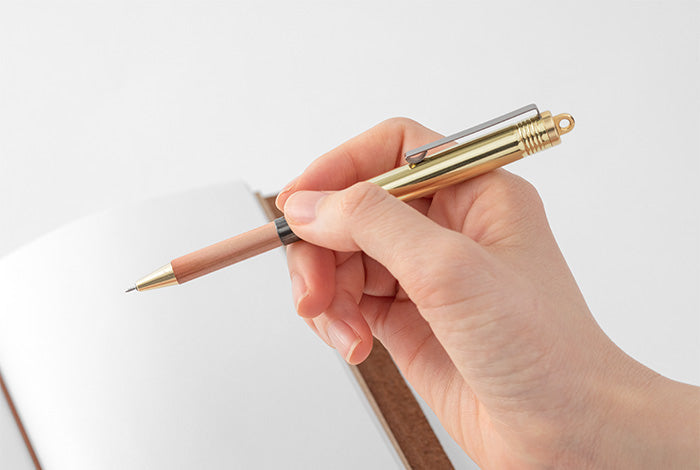 brass ballpoint pen ready to write held by a female hand