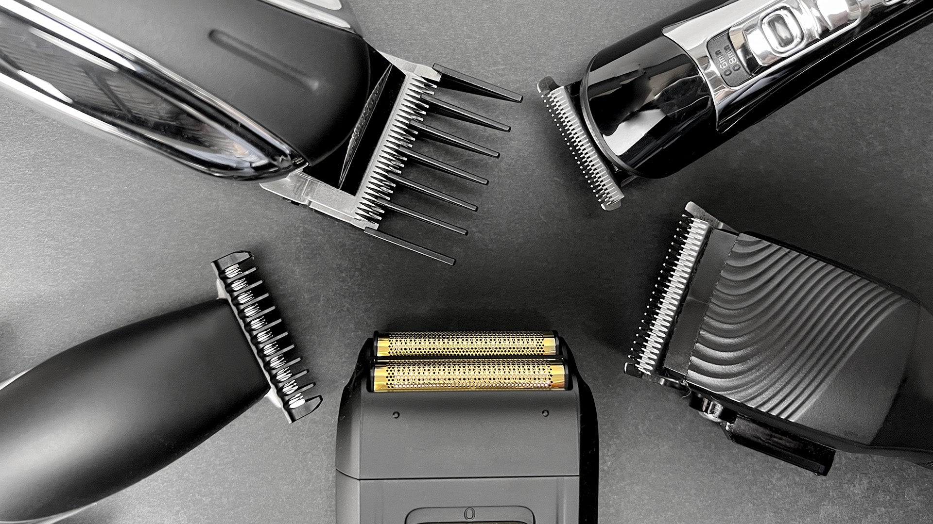 Hair clippers and trimmers and a foil shaver all pointing inward, black and white with gold foil parts of the shaver
