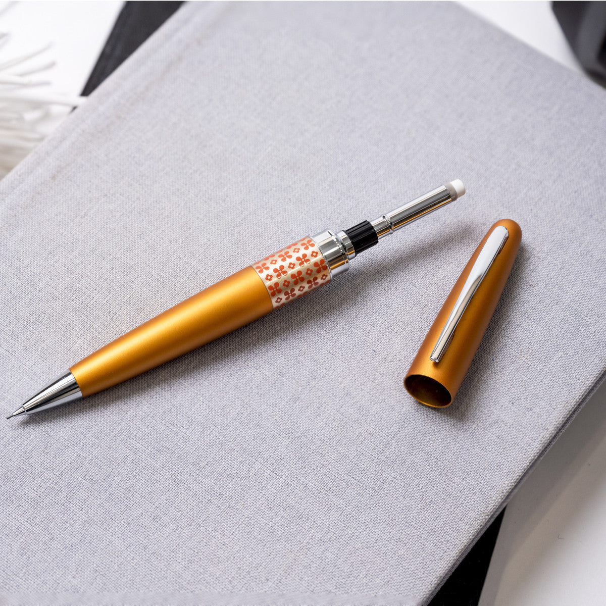 Gold pen with patterned clip on a gray surface