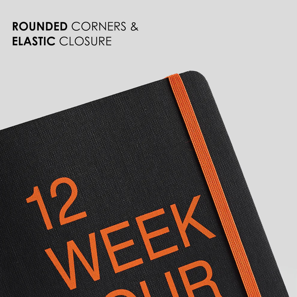 Black notebook with orange text and elastic closure on a light gray background