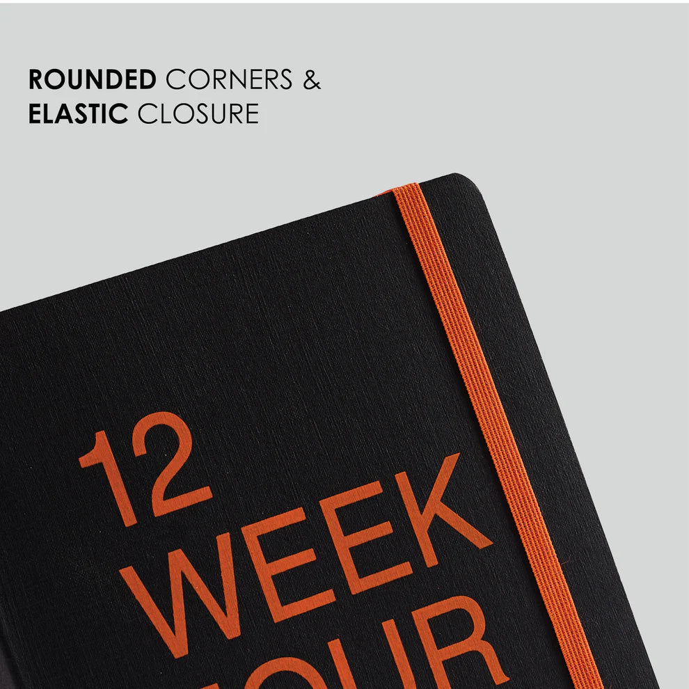 Black notebook with orange text and elastic closure on a light gray background