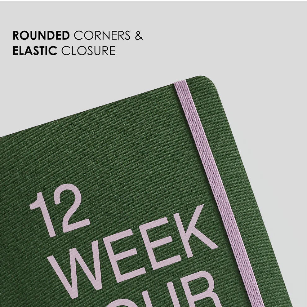 Green notebook with '12 Week Our' text and elastic closure on a light gray background