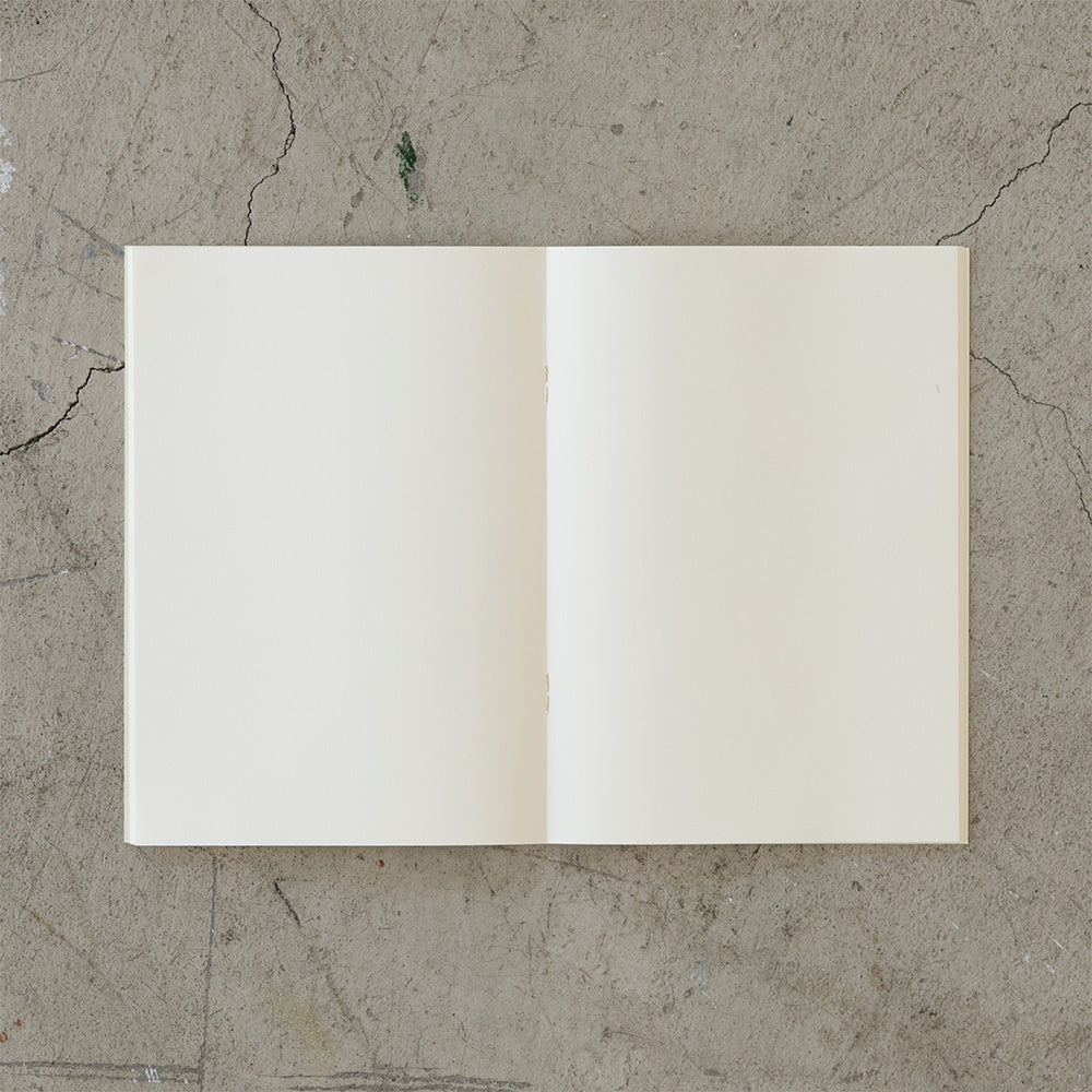 on a slab of aged cement is an open blank notebook viewed top-down