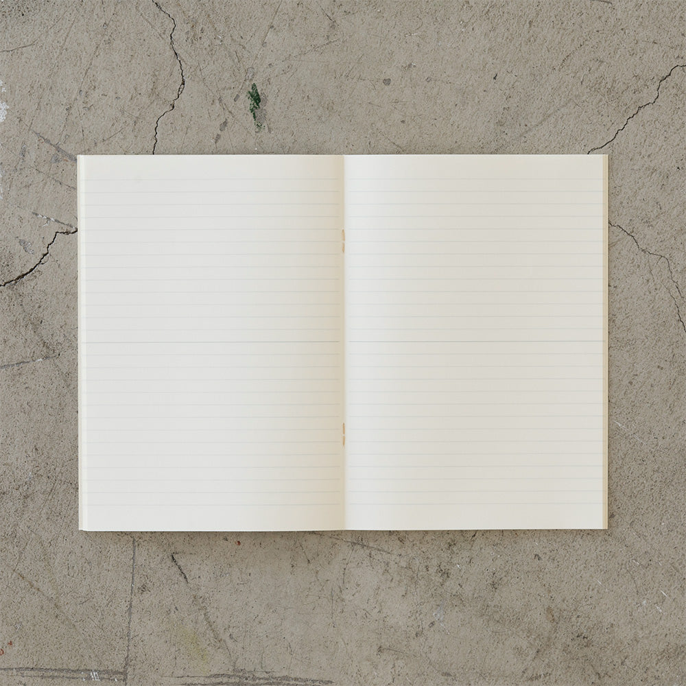 on a slab of aged cement is an open lined notebook viewed top-down