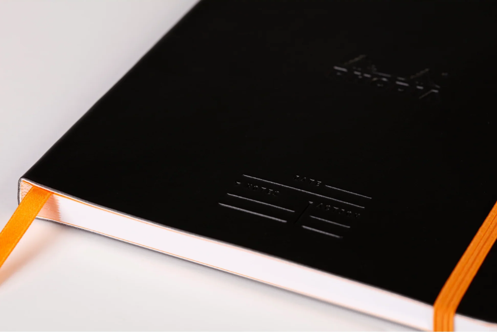 Black notebook with orange binding on a white background