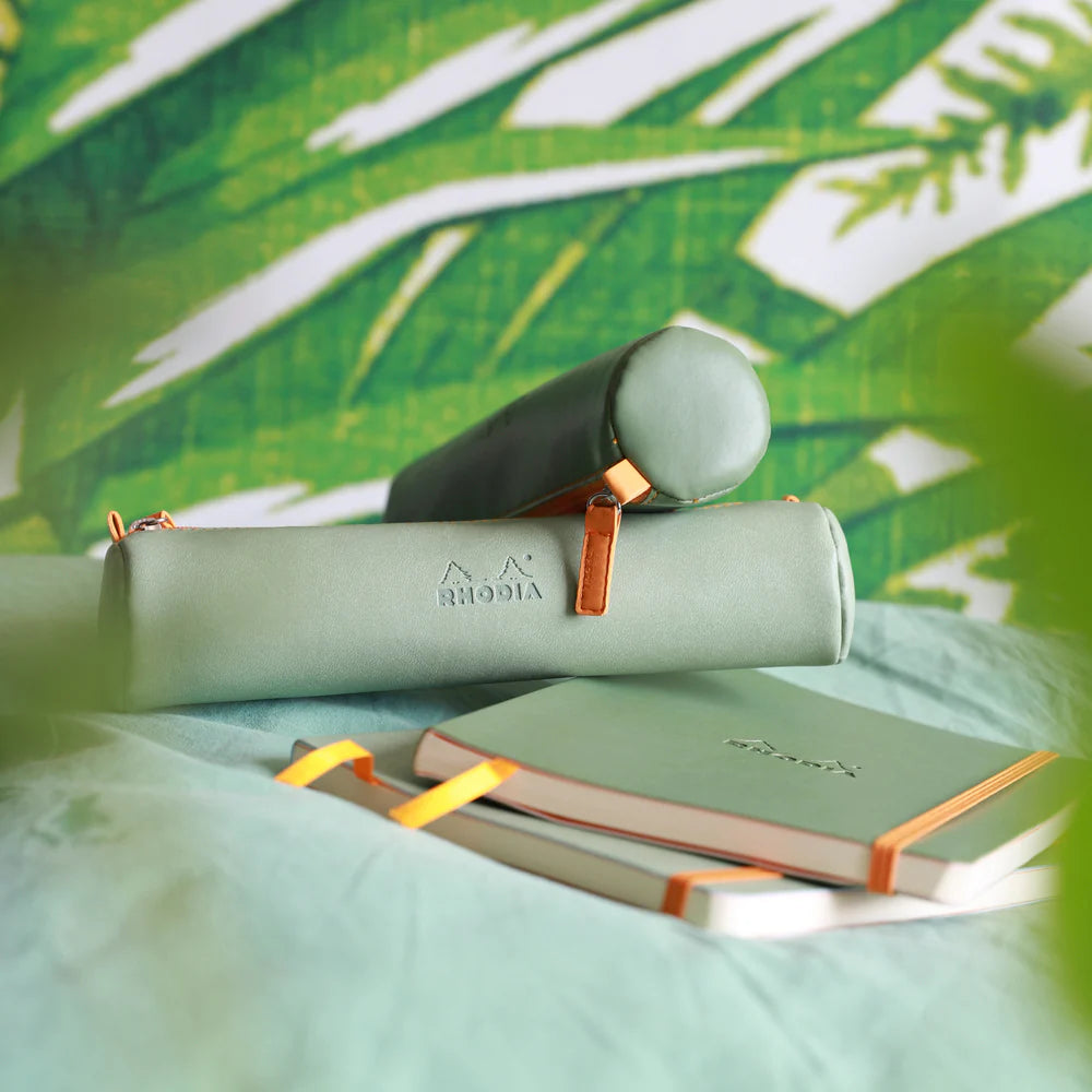 Green leather-bound books with gold accents on a green leafy background