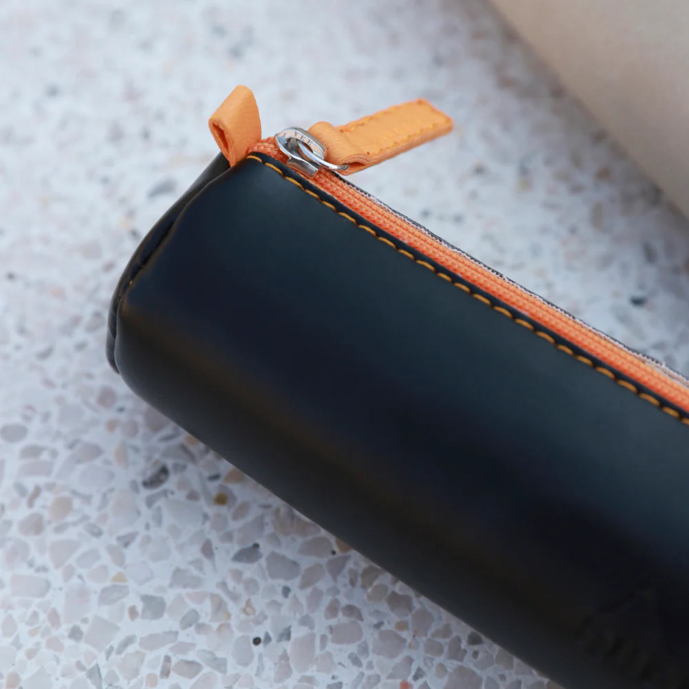 Black pouch with orange zipper on a textured surface