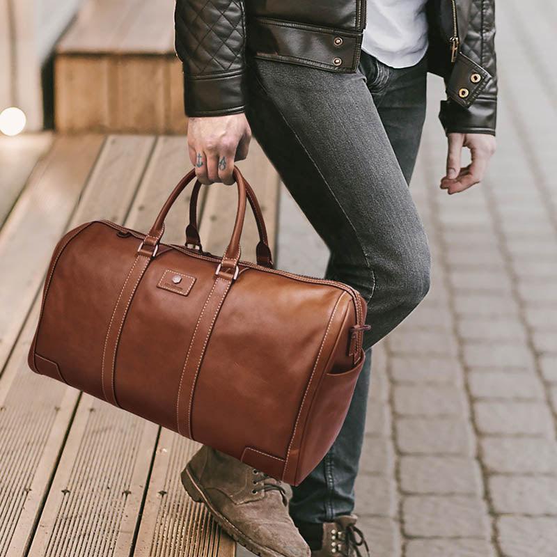 Casually dressed man holding Jekyll &amp; Hide&#39;s large cabin holdall in dark tan leather