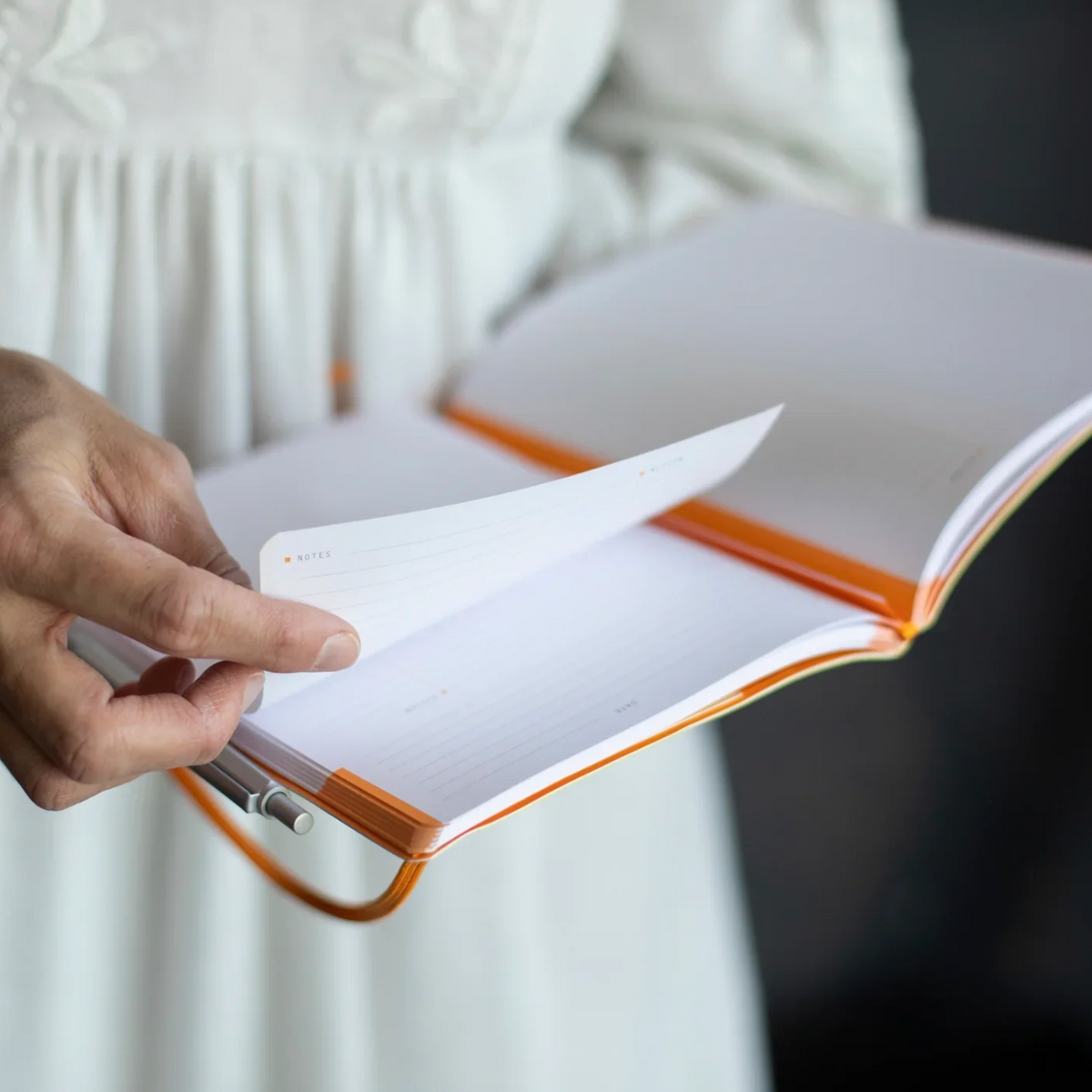 Person holding an open notebook with a white background