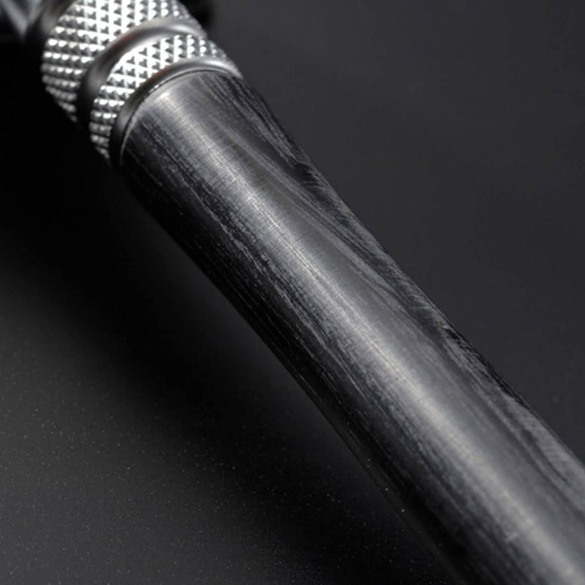 Close-up of a black cylindrical object with textured grip on a dark background