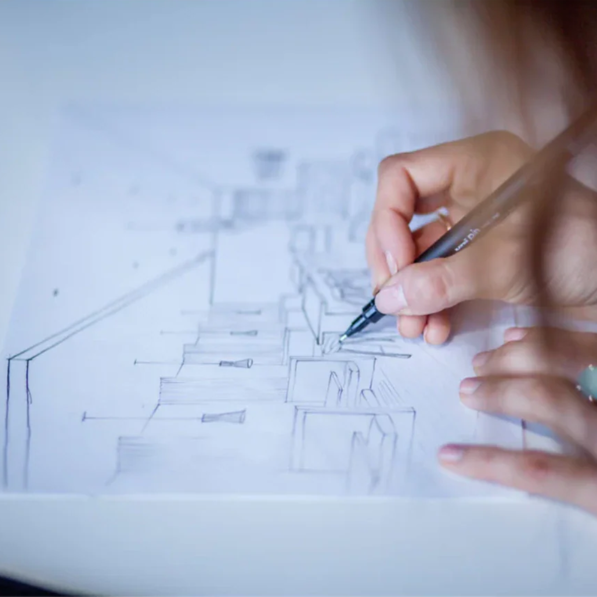 Hand holding a pen over architectural drawings on paper