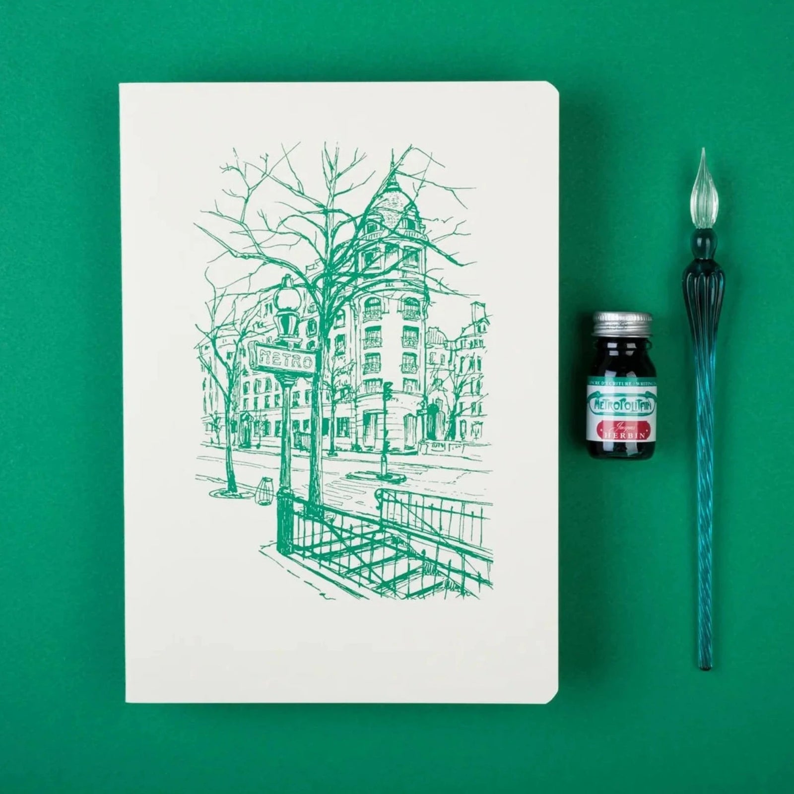 Notebook with green line art of a city street scene on a white background