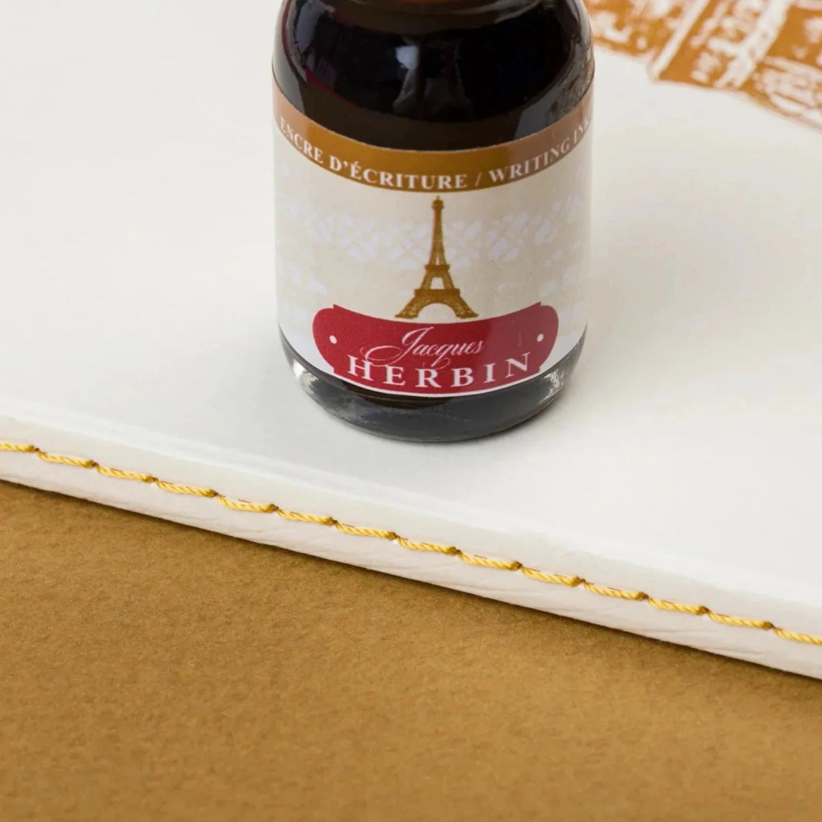 Ink bottle with Herbin label on a textured surface