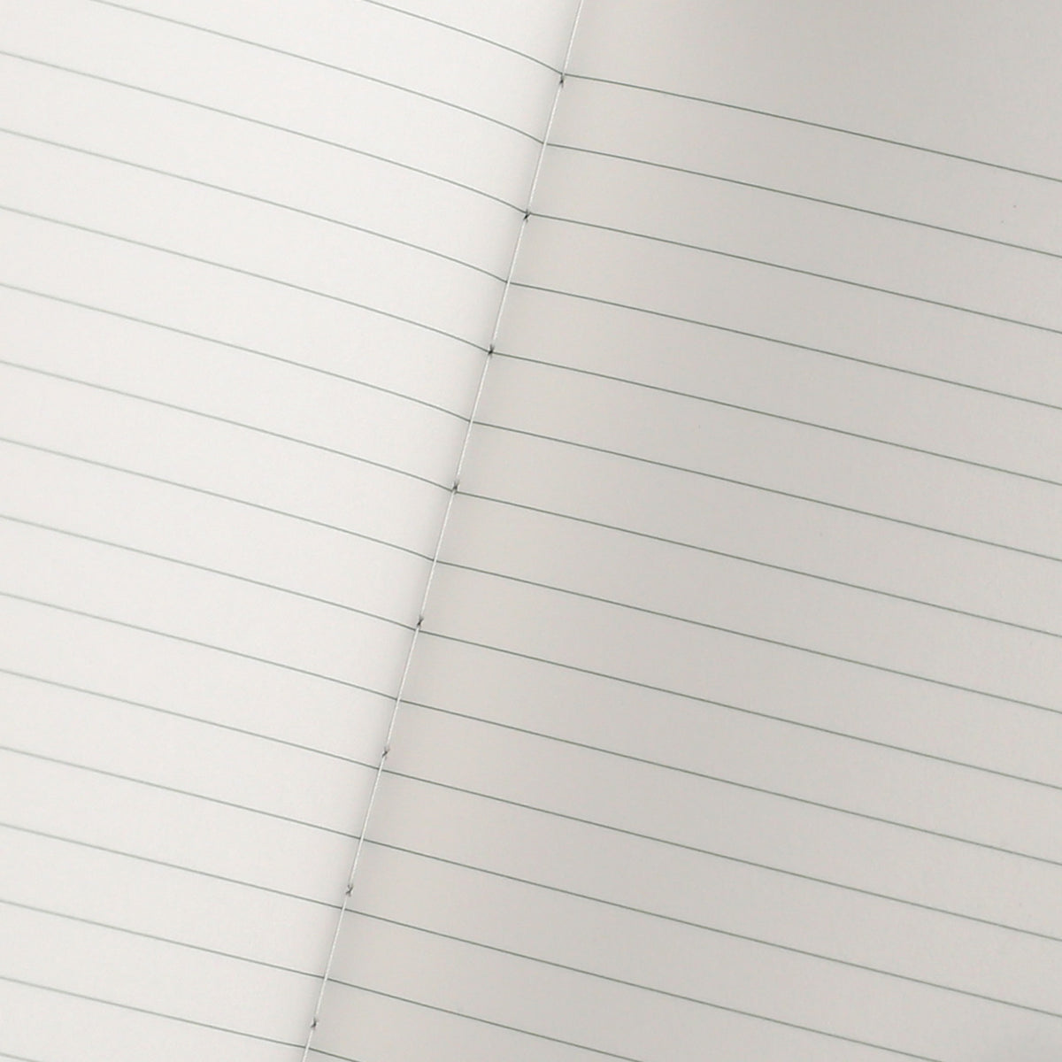 detail of an open notebook showing the gray printed lines and white stitching