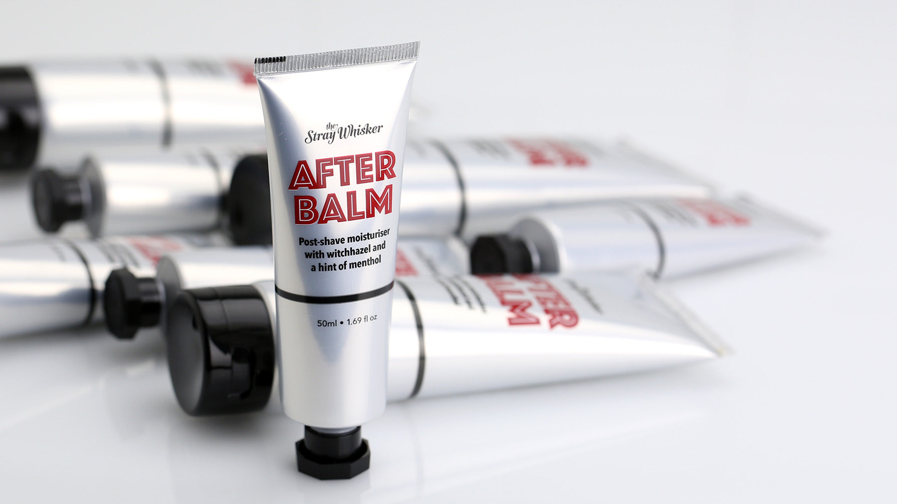 silver tubes of After Balm on a reflective white background