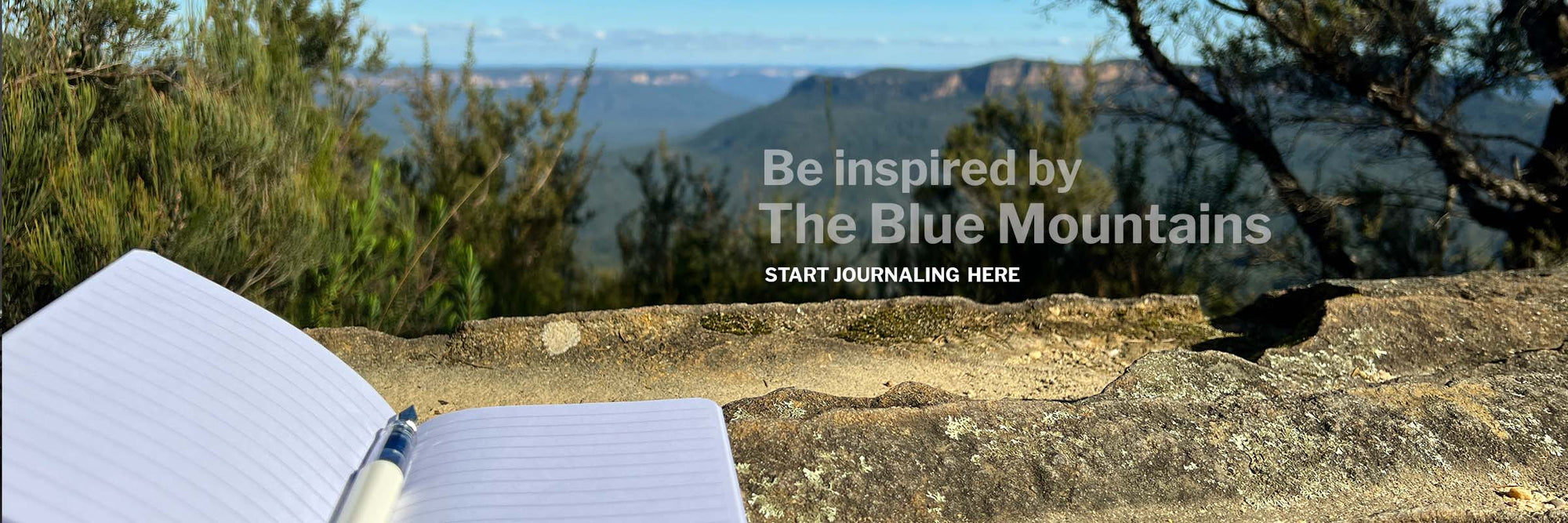 Be inspired by The Blue Mountains, a photo of an open lined journal with a fountain pen on top, on sandstone at Olympian Rock Lookout, Leura, in the Blue Mountains
