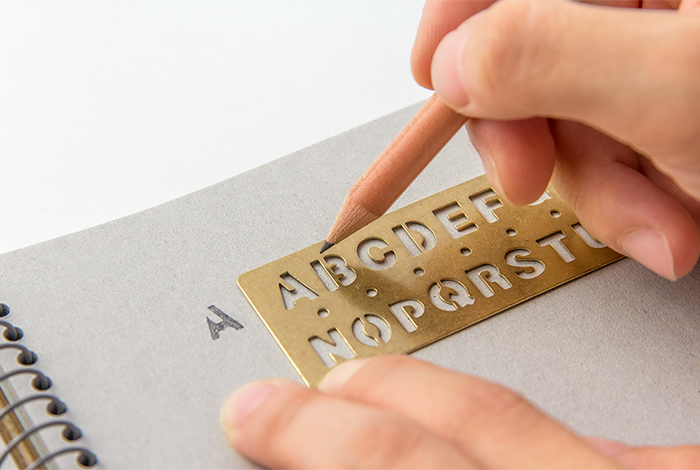Person using a brass letter stamper on a notebook