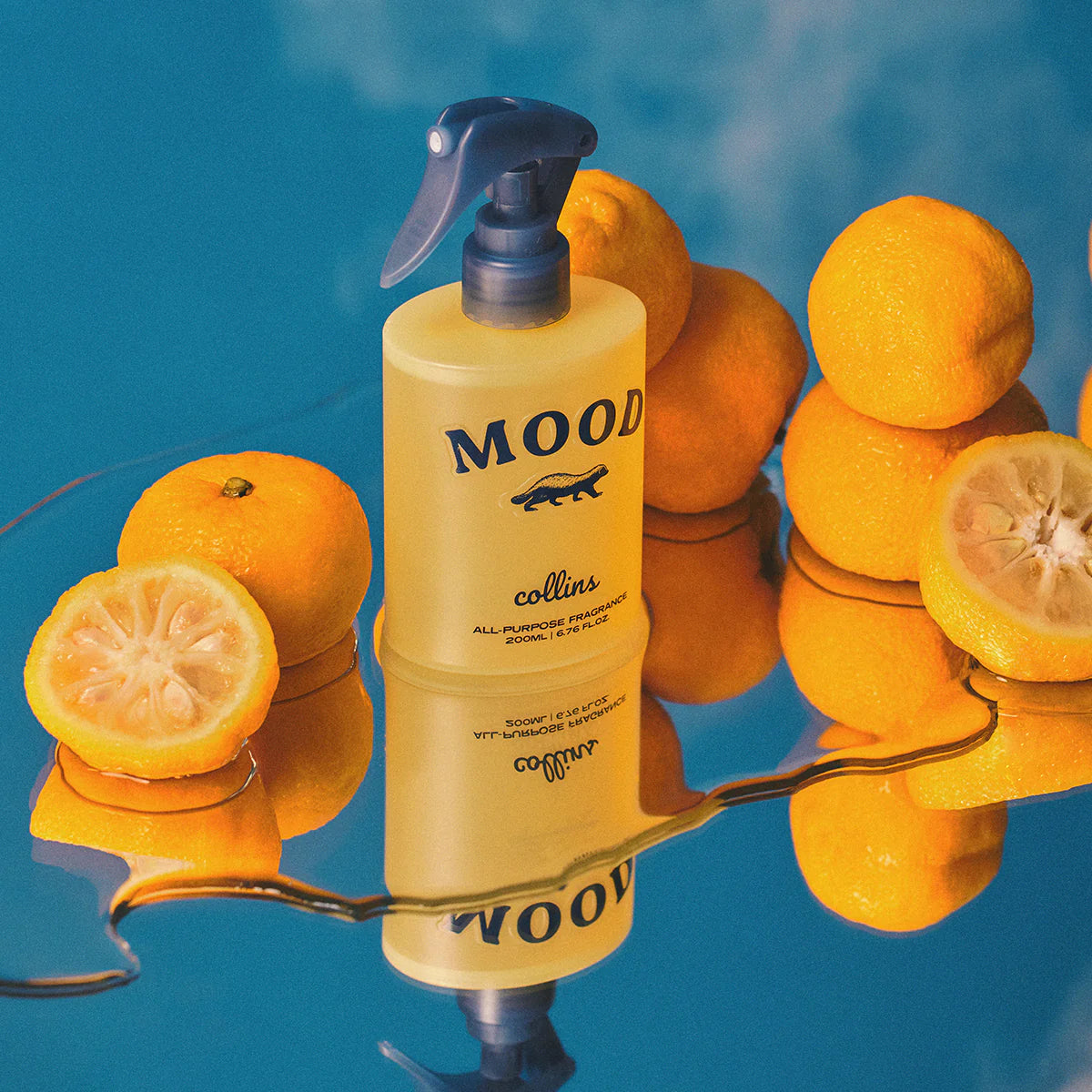 Yellow bottle labeled 'MOOD' with oranges and lemons on a reflective surface