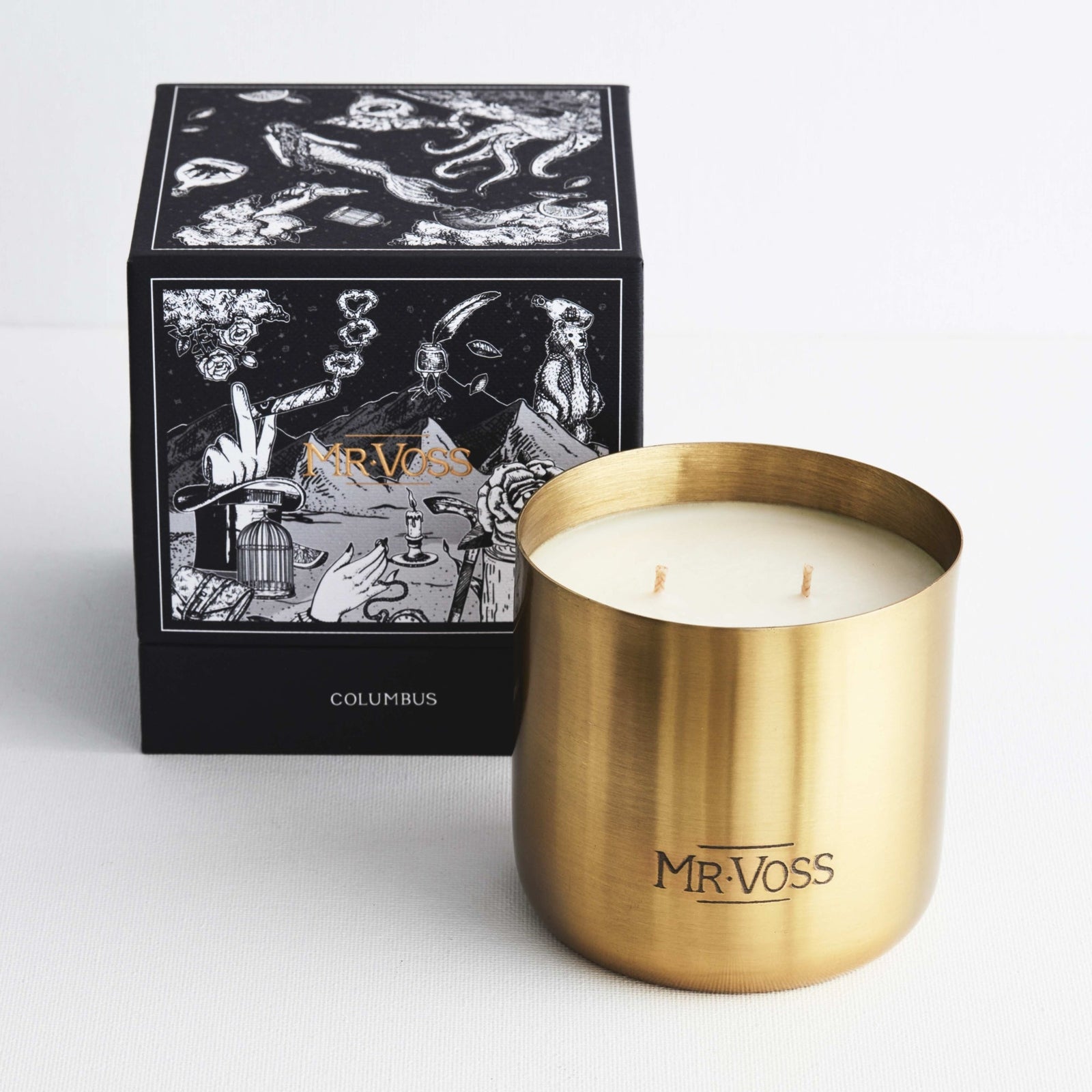 Gold candle holder with white candle and decorative box labeled 'MR. VOSS' on a light gray background