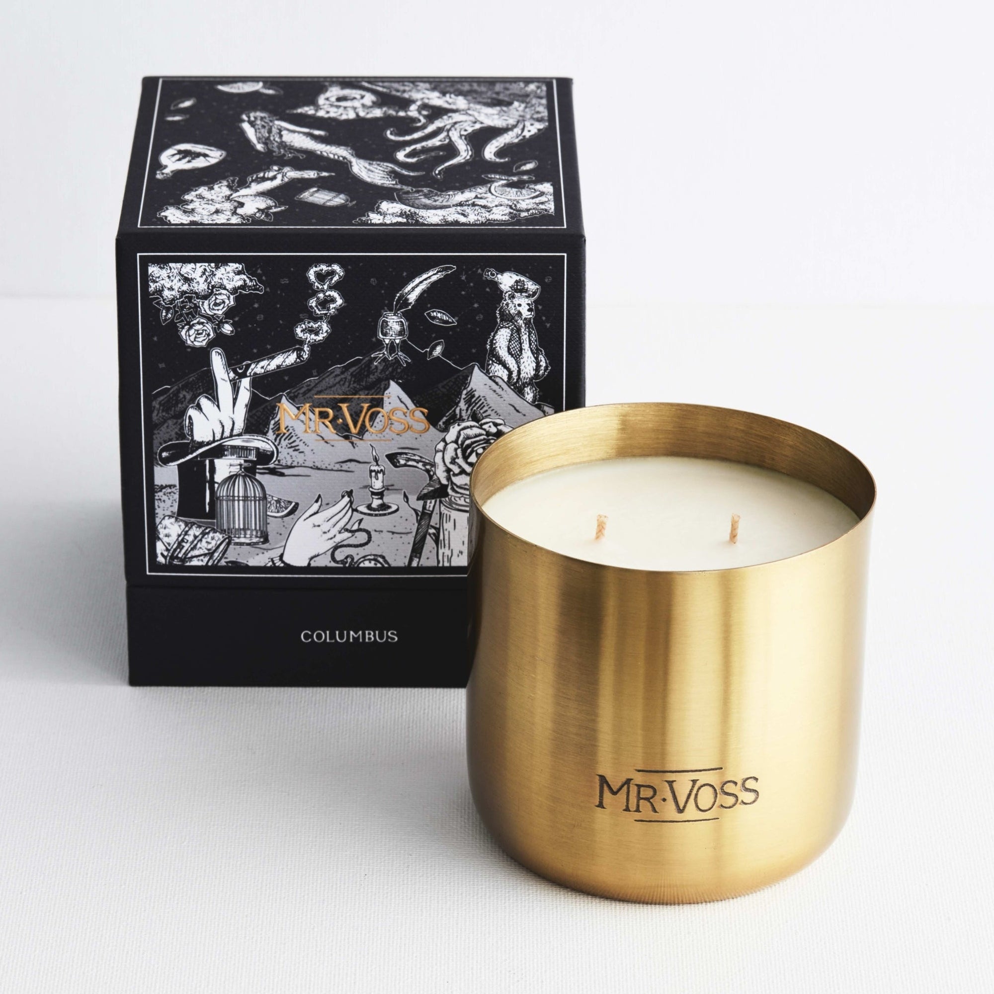 Gold candle holder with white candle and decorative box labeled 'MR. VOSS' on a light gray background