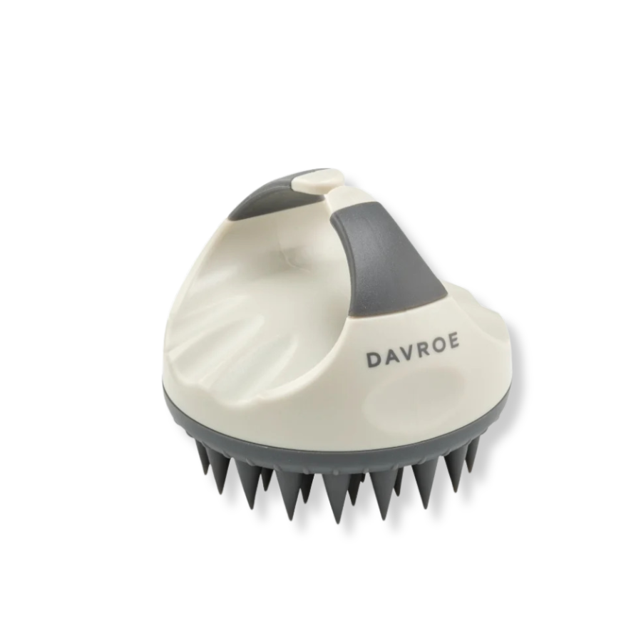 A Davroe scalp massage brush with a cream-colored plastic body, dark gray silicone handle and bristles, and the brand name 'DAVROE' printed on the side, set against a plain white background.