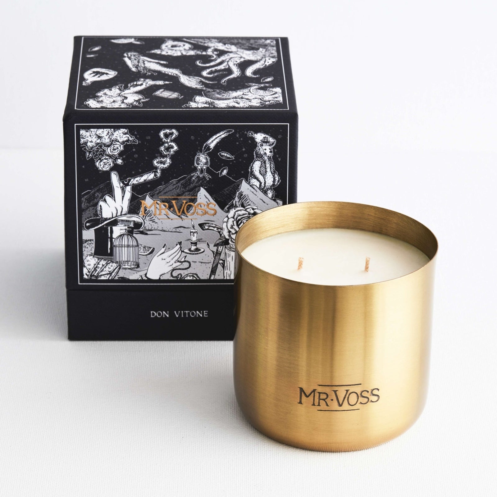 Gold candle with 'MR. VOSS' branding next to its packaging on a white background