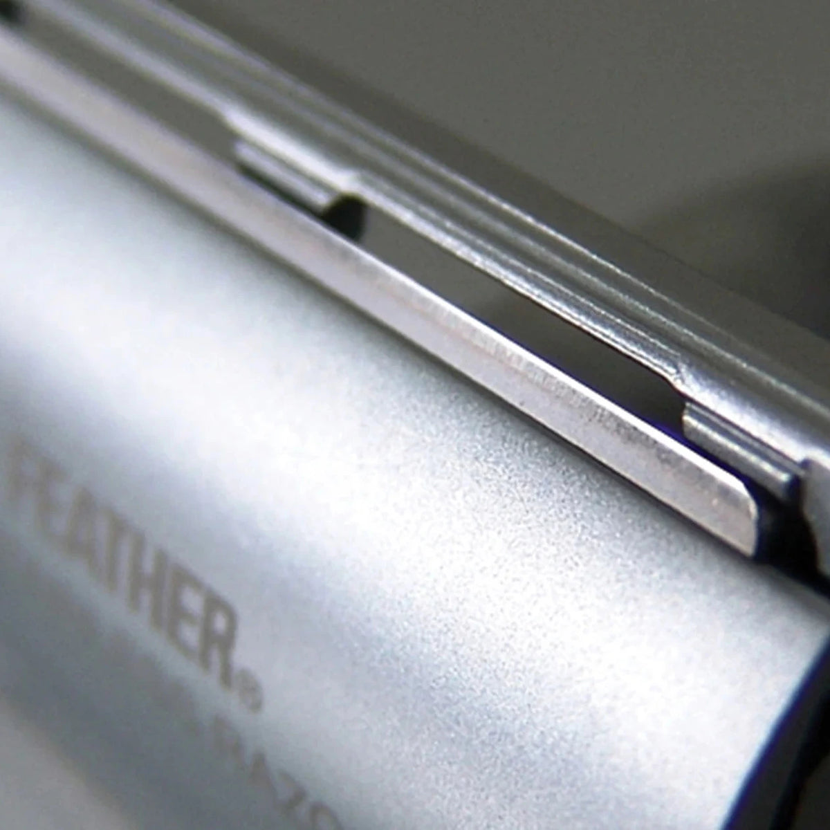 Close-up of a metallic device with 'FEATHER' branding on a blurred background