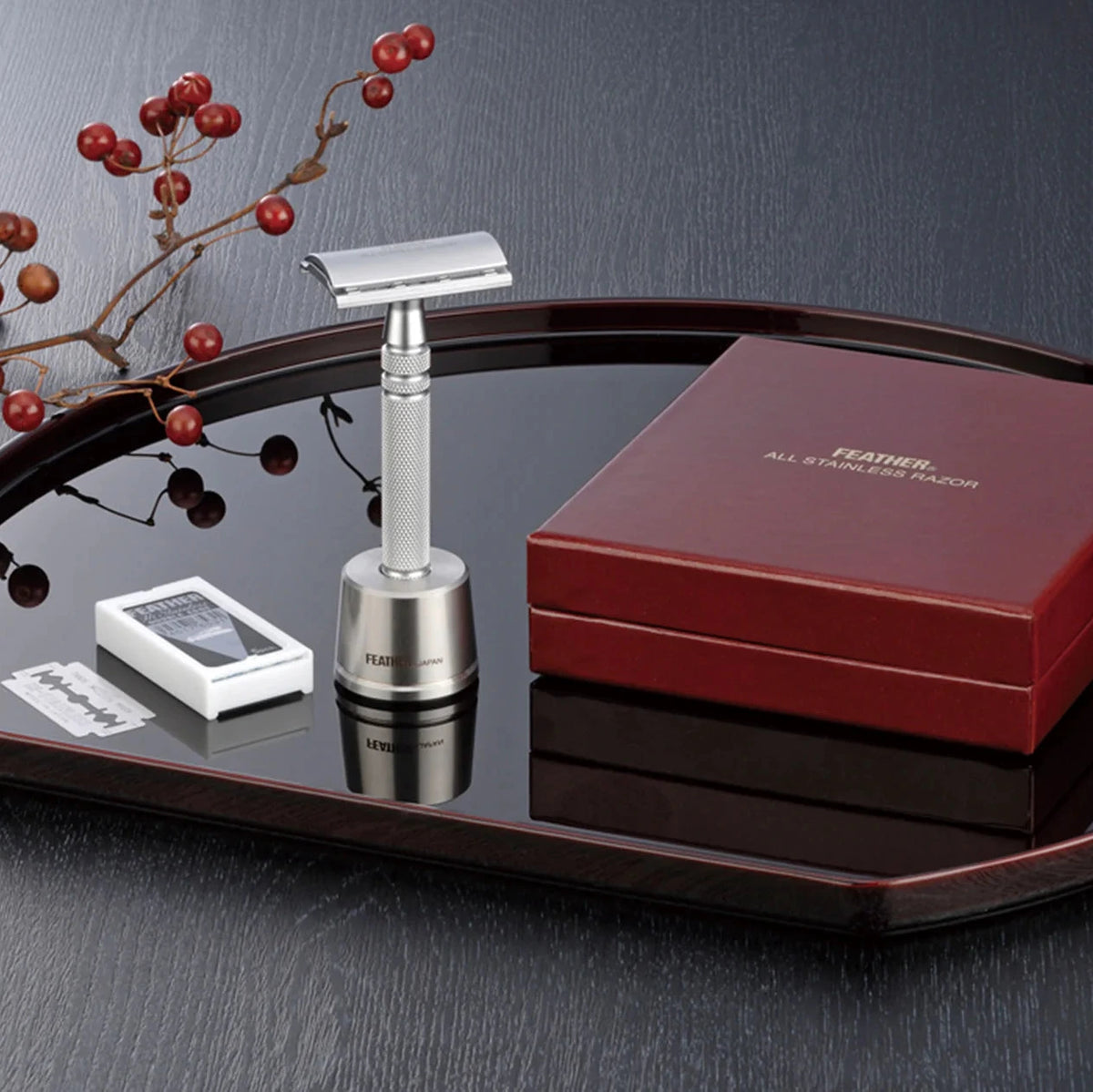 Silver safety razor with red Feather box on a dark surface