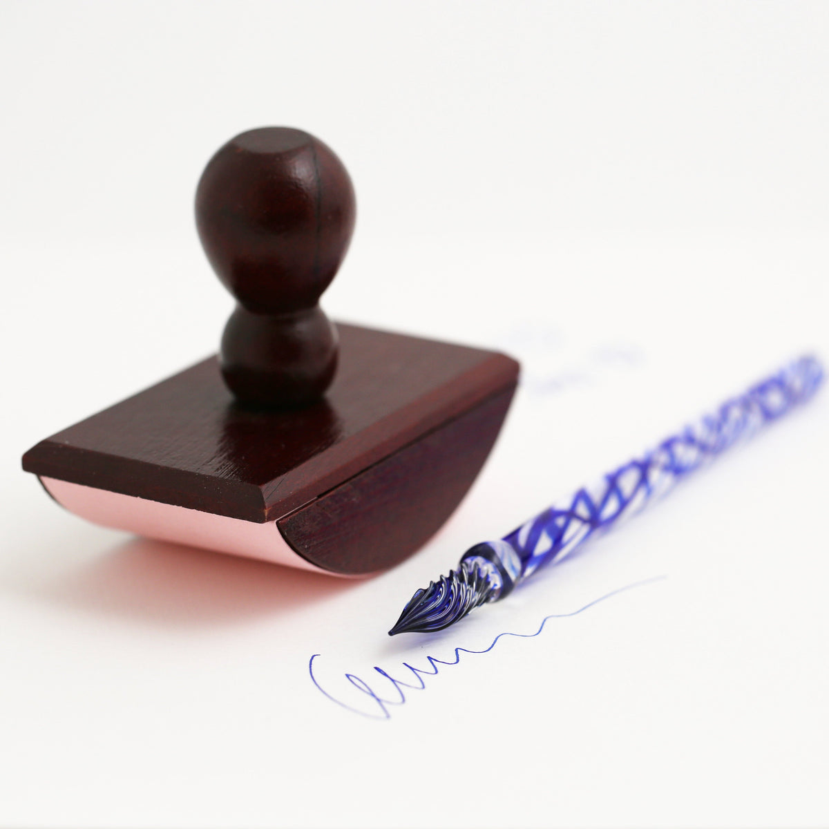 Rocking wooden blotter stamp with a blue glass dip pen on paper