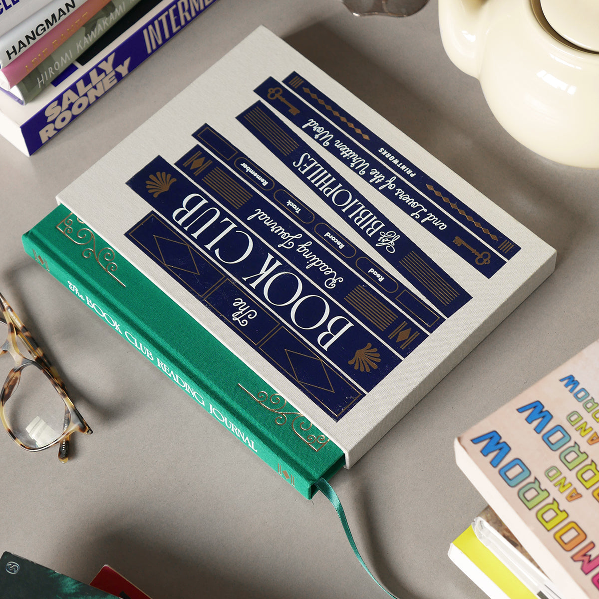 Book with decorative cover on a surface with glasses and other books.