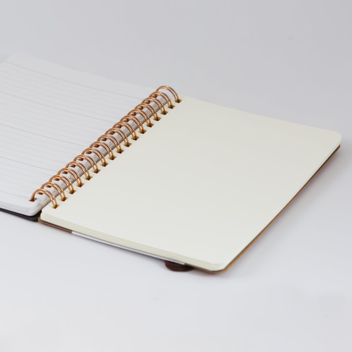 Open B6 notebook showing the cream coloured blank Midori page section, and copper coloured wire binding