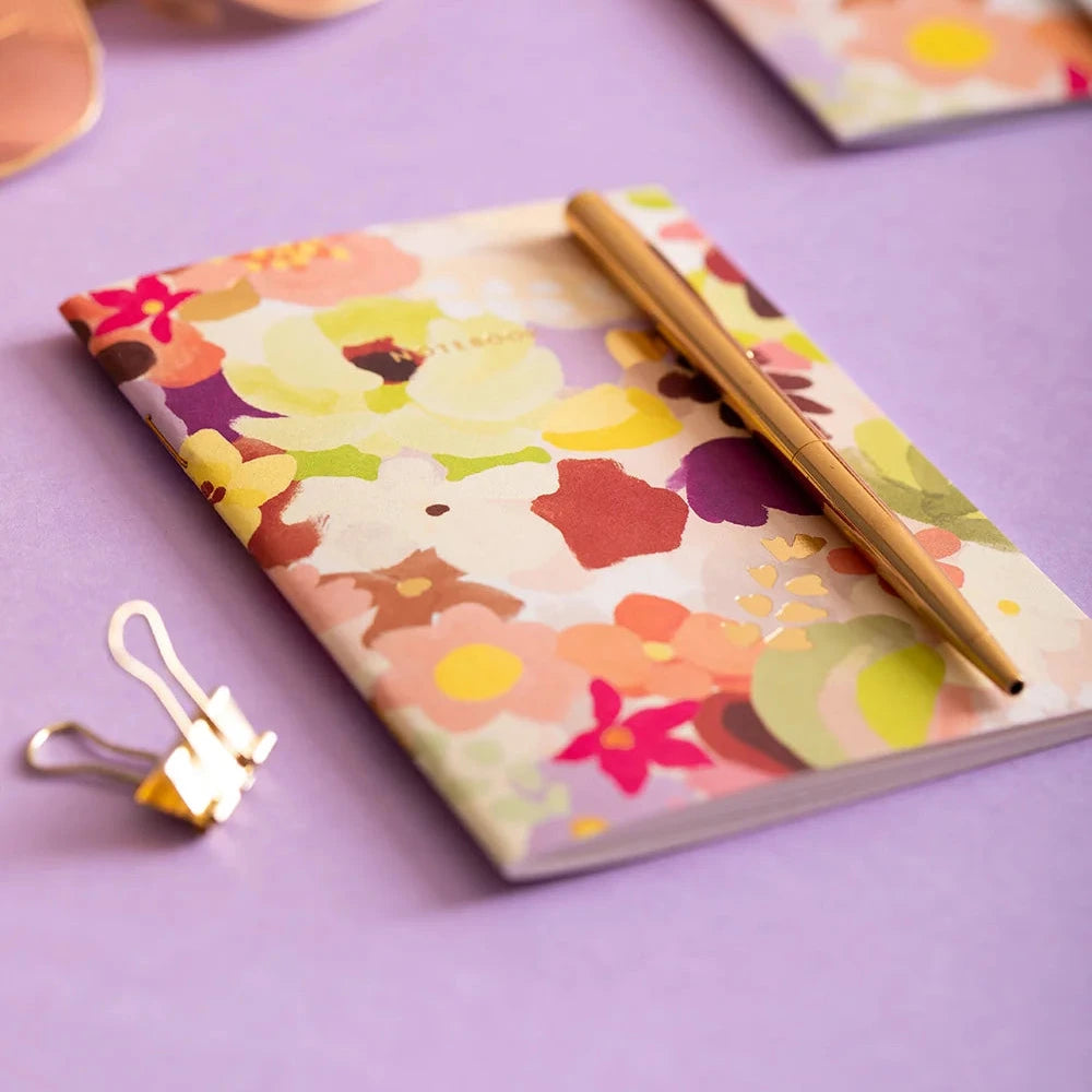 Colorful floral notebook with a pen on a purple surface