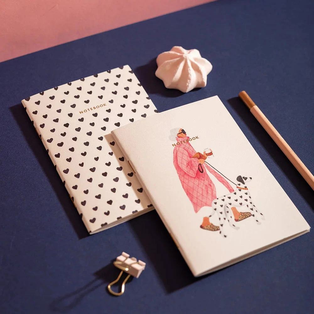 Two notebooks on a blue surface with a pink background