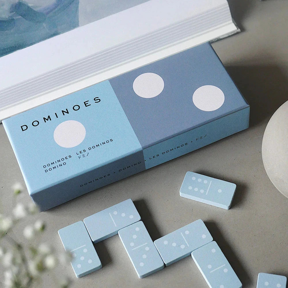 Blue domino set with packaging on a neutral surface