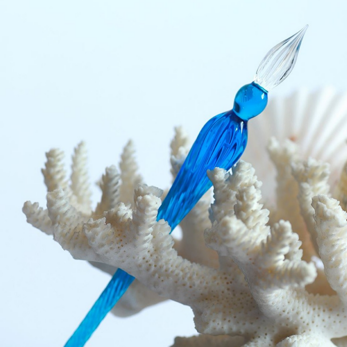 Blue glass pen on a piece of white coral with a light blue background