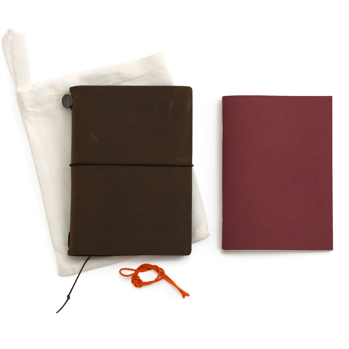 Brown leather notebook in passport size with the blank notebook which fits inside, an extra orange elastic and the cotton bag