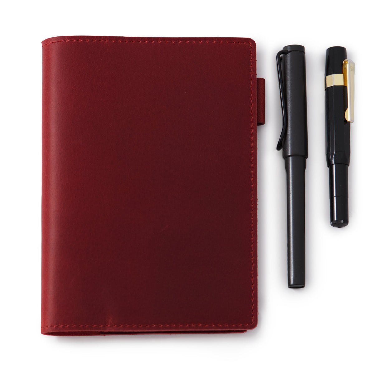 red leather A6 notebook cover shown with a Lamy and a Kaweco Sport pen for scale. Pens sold separately