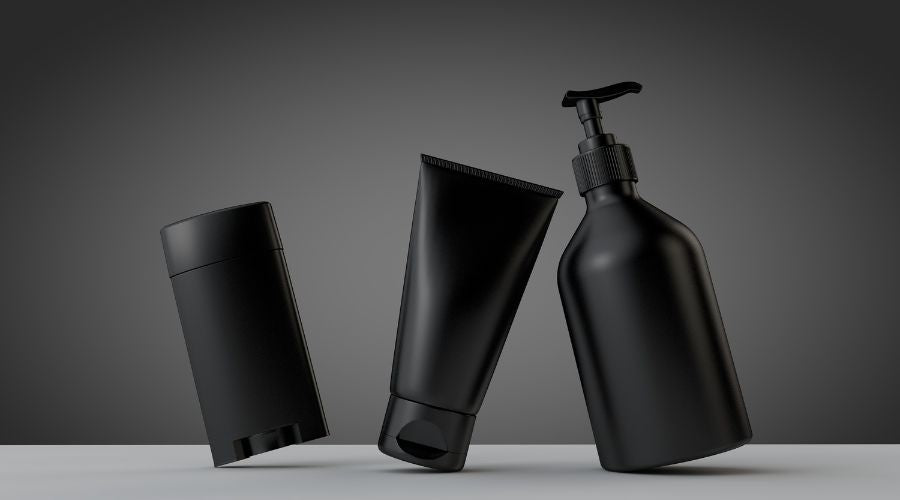 Three black skincare products on a gray background