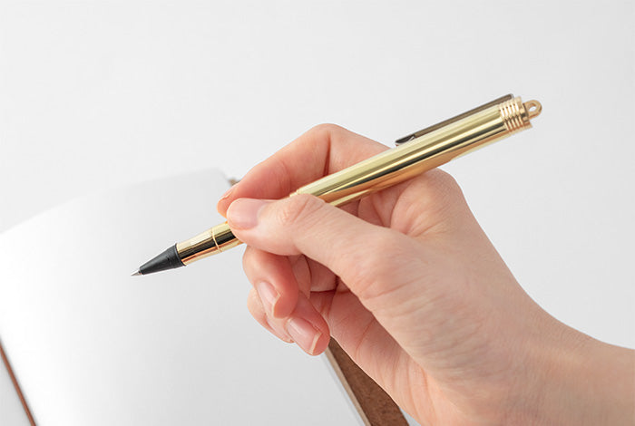 hand holding the rollerball brass pen
