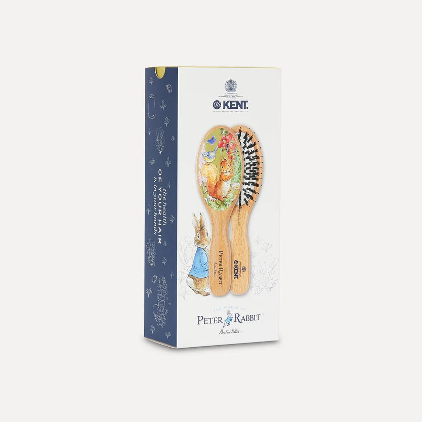 Kent Peter Rabbit hairbrush set in its original retail packaging, featuring two wooden hairbrushes with colorful Peter Rabbit illustrations and black bristles, on a light gray background.