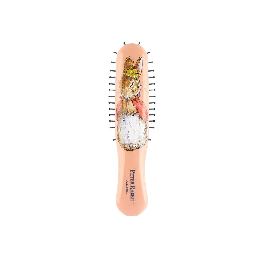 A peach-colored hairbrush featuring a detailed illustration of Peter Rabbit on the handle, with black bristles and the text 'Peter Rabbit' printed near the bottom.