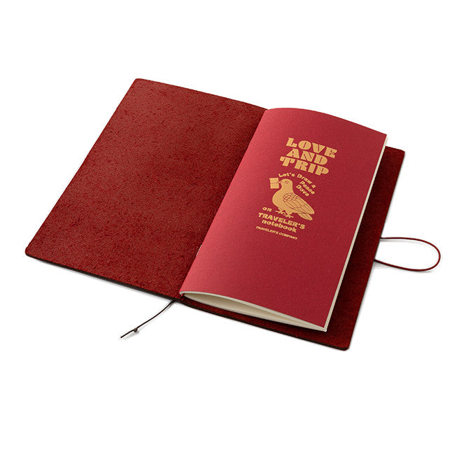 TRAVELER'S notebook with a limited edition Love and Trip design, featuring a vibrant red leather cover with debossed detailing. The product also includes a cardboard packaging, a muslin slip bag, and a limited edition refill booklet with gold foil design.