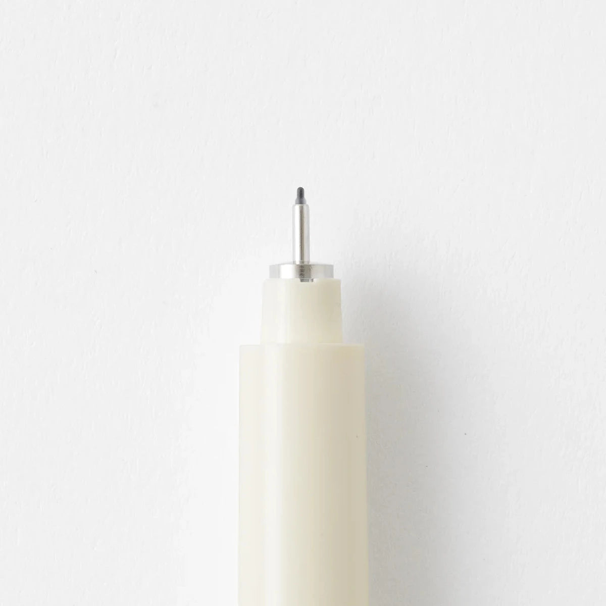 White cylindrical object with a metallic top on a light gray background
