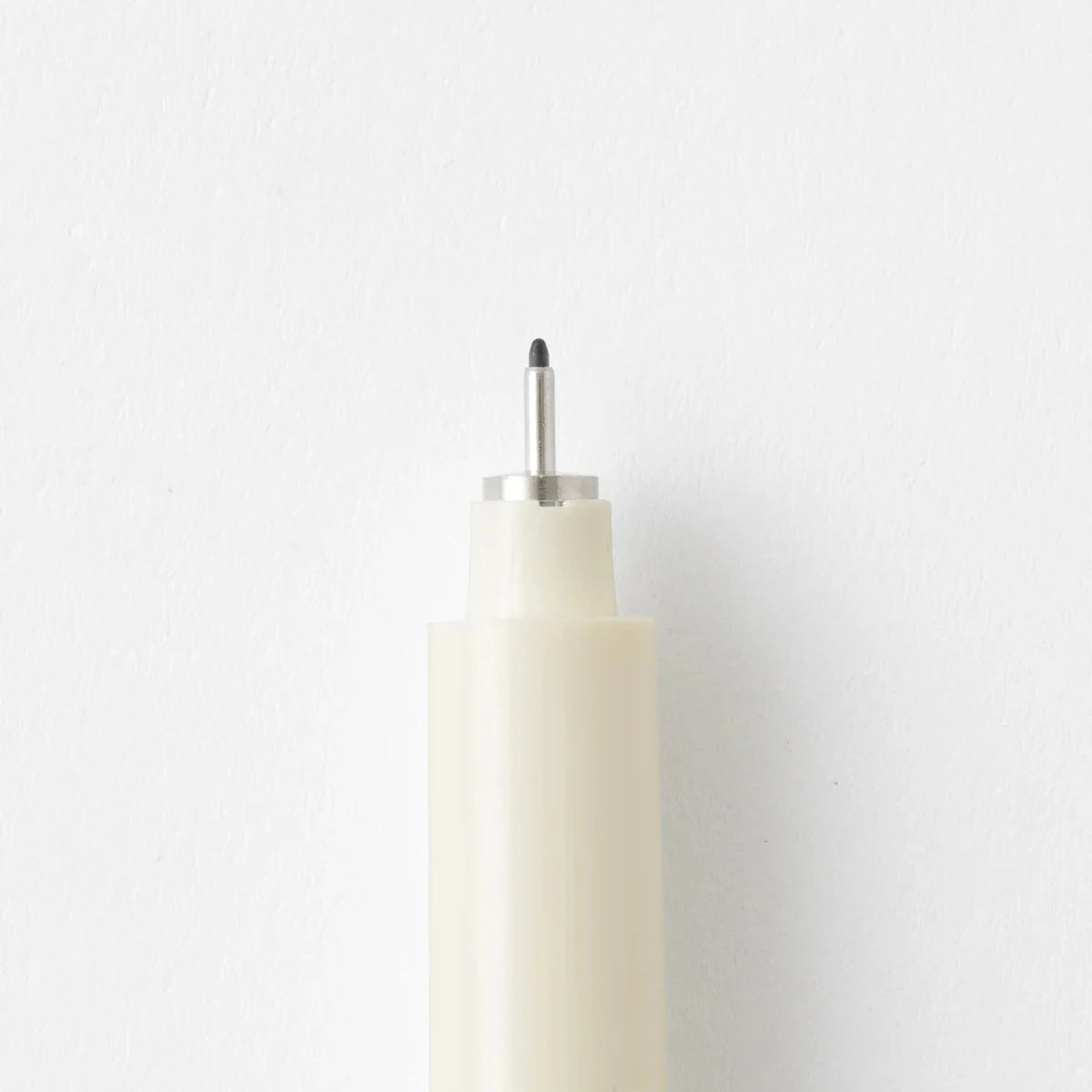 White cylindrical object with a black tip on a light gray background