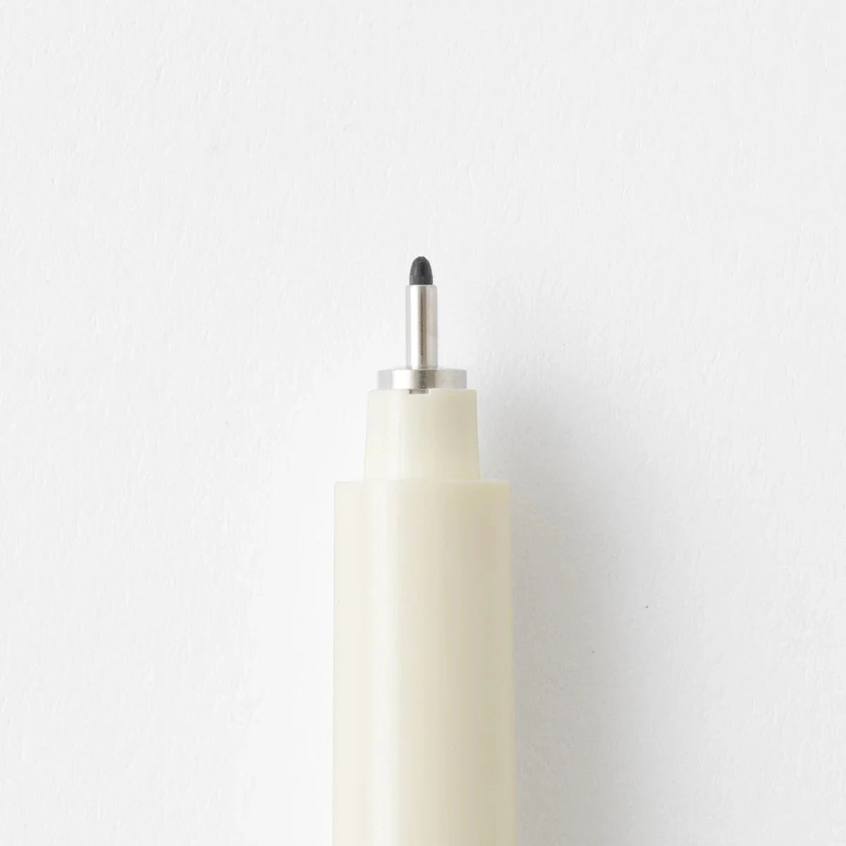 White cylindrical object with a black tip on a light gray background