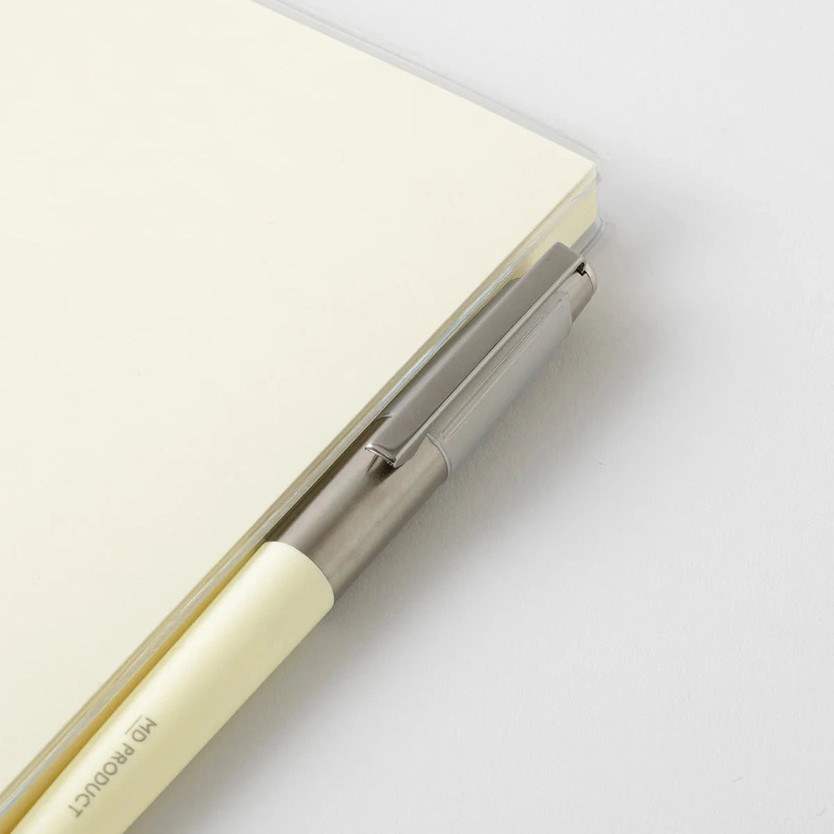 Close-up of a light beige notebook with a metallic clip on a white background