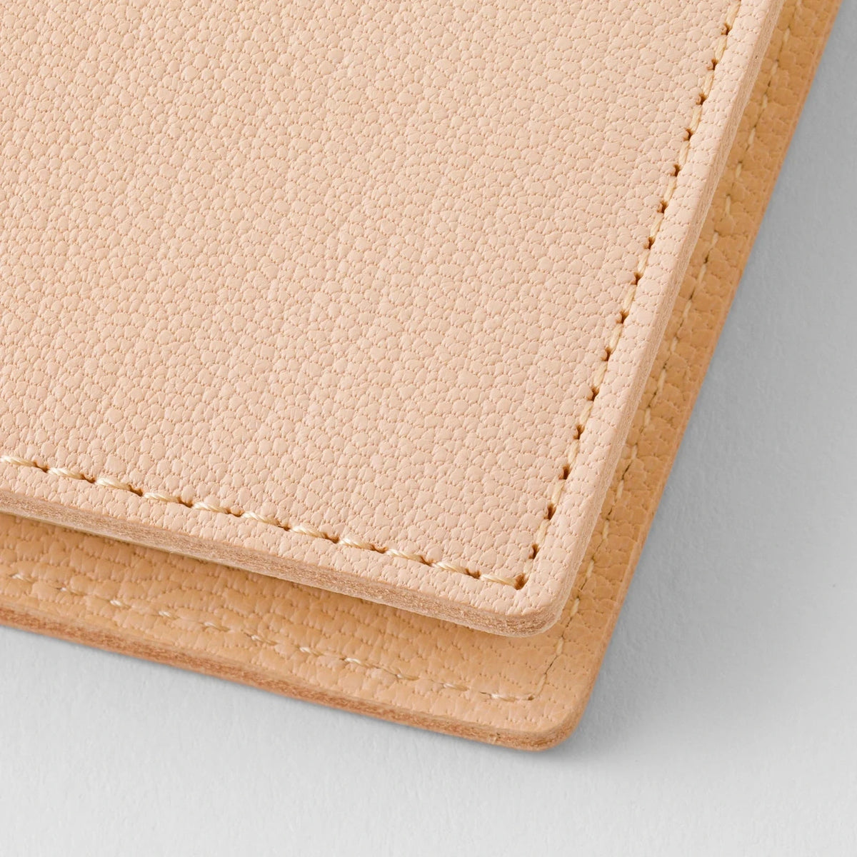 Close-up of a beige leather wallet with visible stitching on a light gray background
