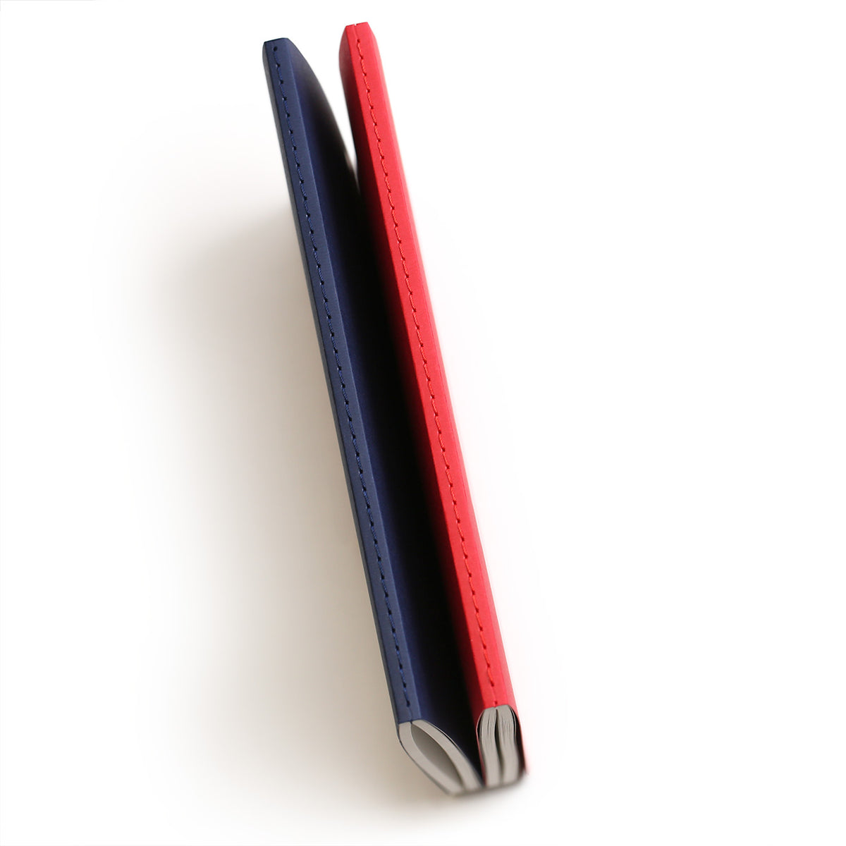 The outer spines of a red and blue refill notebook showing the matching colured stitching