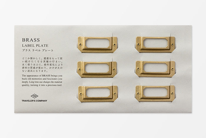 Set of gold brass label plates on a white card with text and branding.