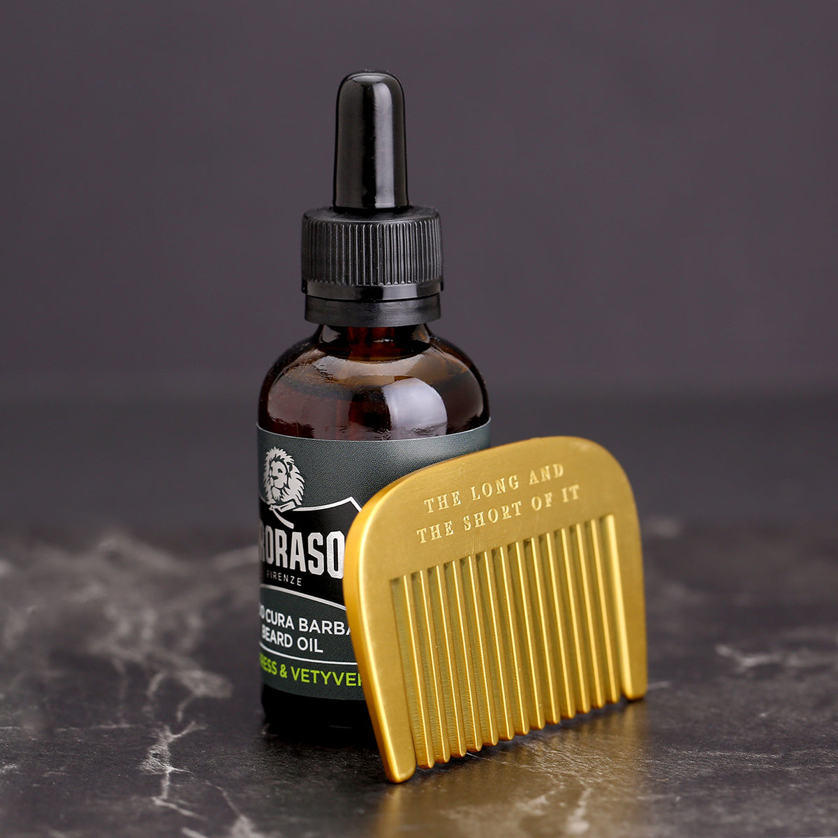 Brass beard comb shown next to a bottle of Proraso Beard Oil for size reference. Beard oil not included
